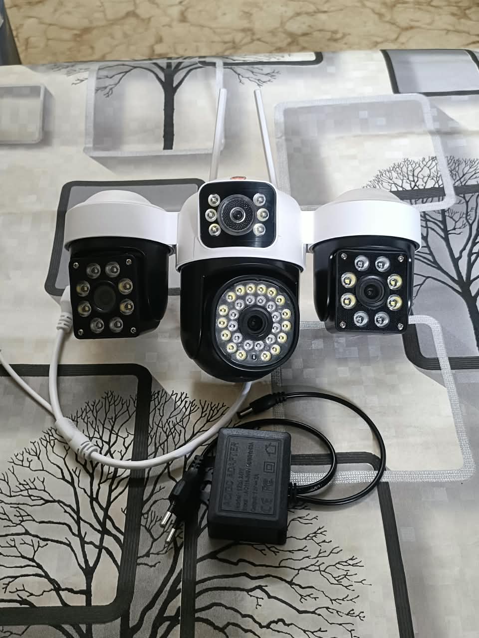 White and black multi-lens 4G PTZ security camera with power adapter